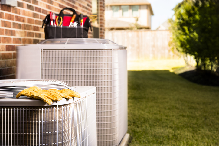 Bag of repairman's work tools, gloves on top of air conditioner units